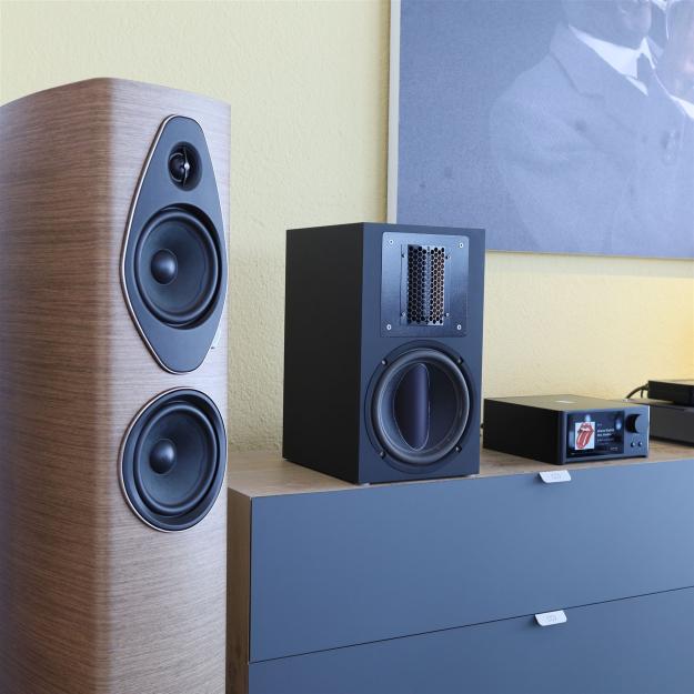 Die Swiss-HD Solo 6 spielbereit platziert auf einem Swiss-HD Möbel im Wohnzimmer neben einem Sonus faber Sonetto III G2 Standlautsprecher